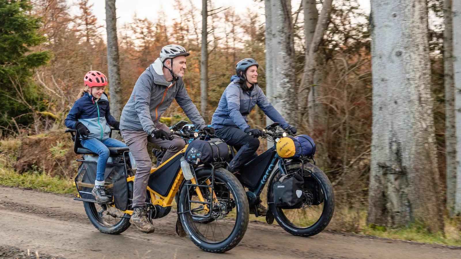 Three people on fat wheel bikes in a forest setting