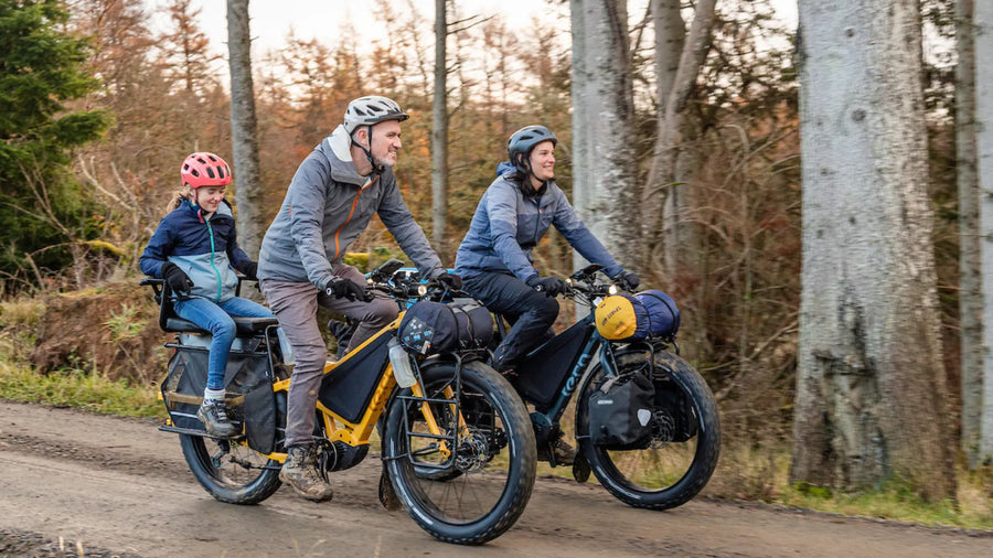 Three people on fat wheel bikes in a forest setting