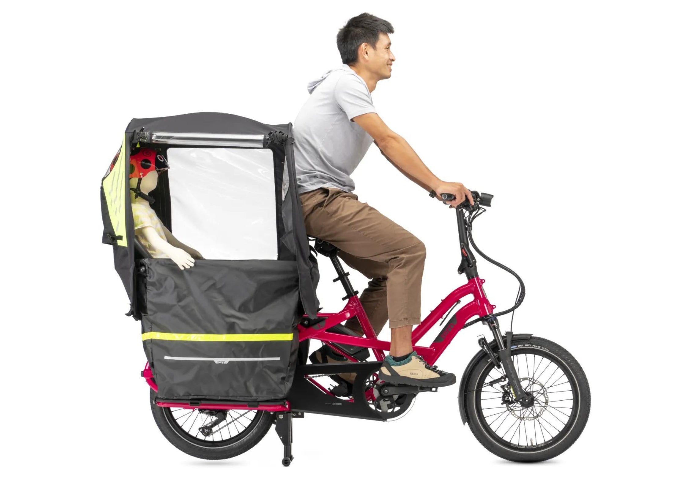 Person riding a Tern cargo bike with a child in a seat on a white background