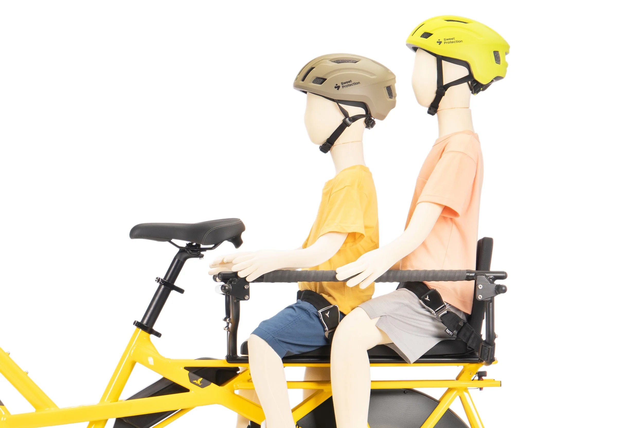 Two mannequins wearing helmets on a tandem bicycle against a white background