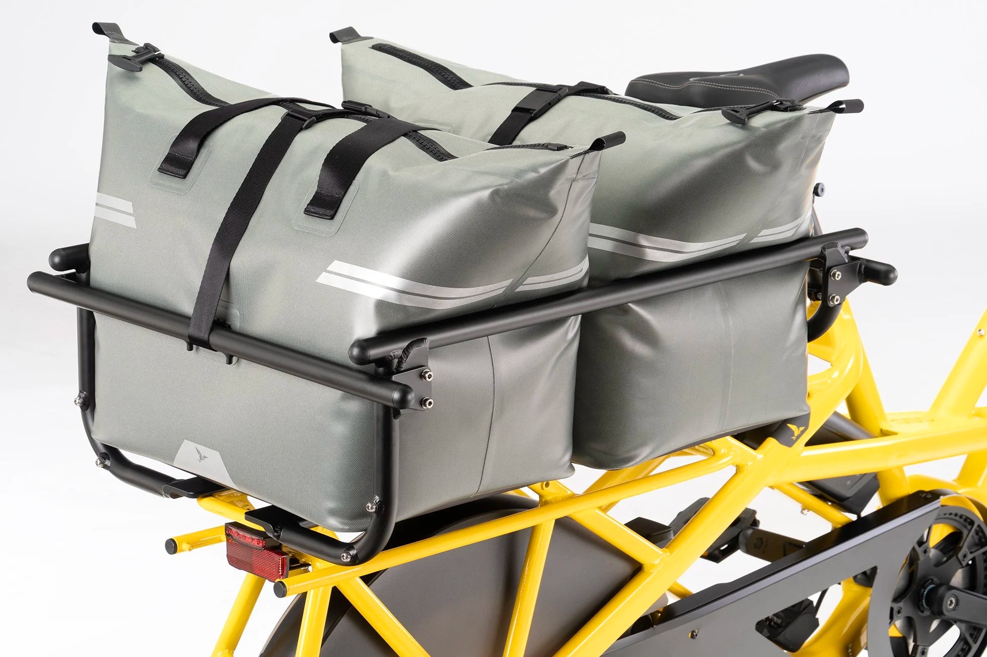 Gray pannier bags attached to a yellow bicycle with a black rack.
