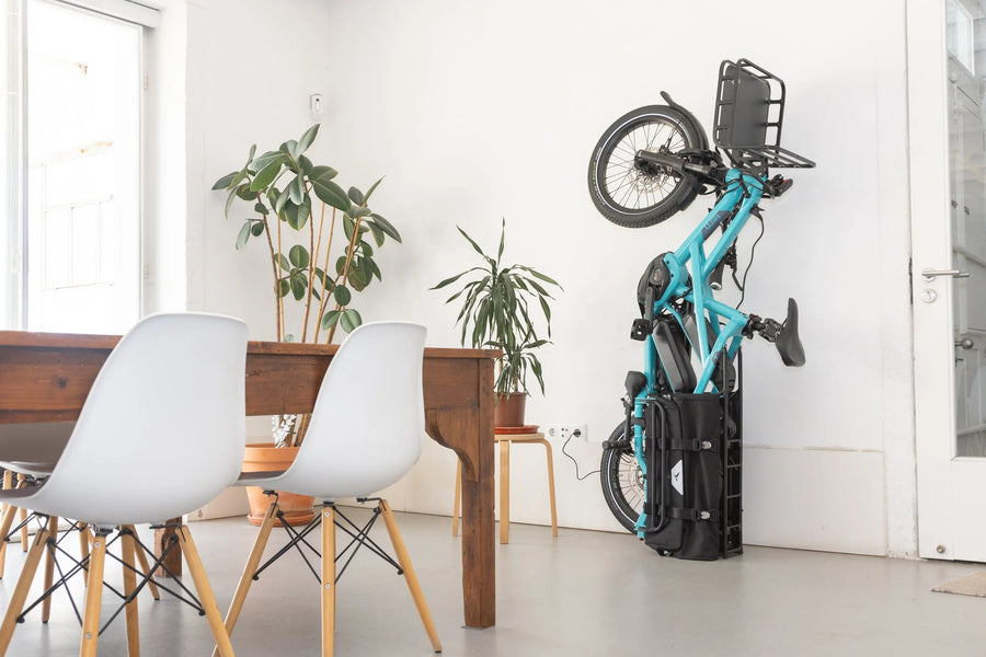Foldable Tern electric bike against a white wall with a modern interior setting.