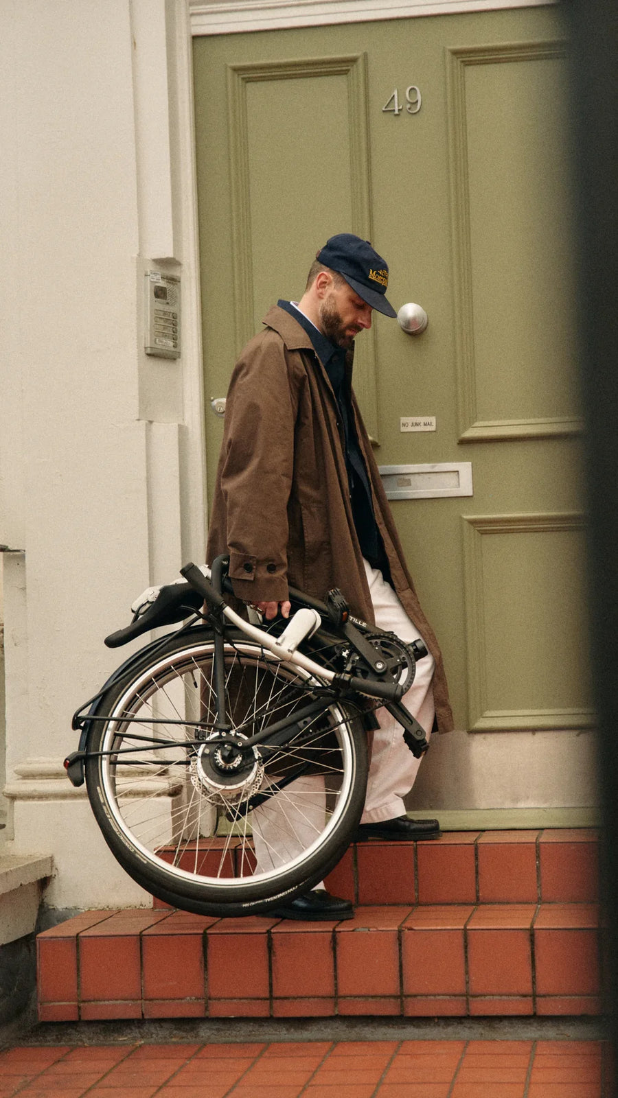 Man with a folded bicycle standing on a doorstep