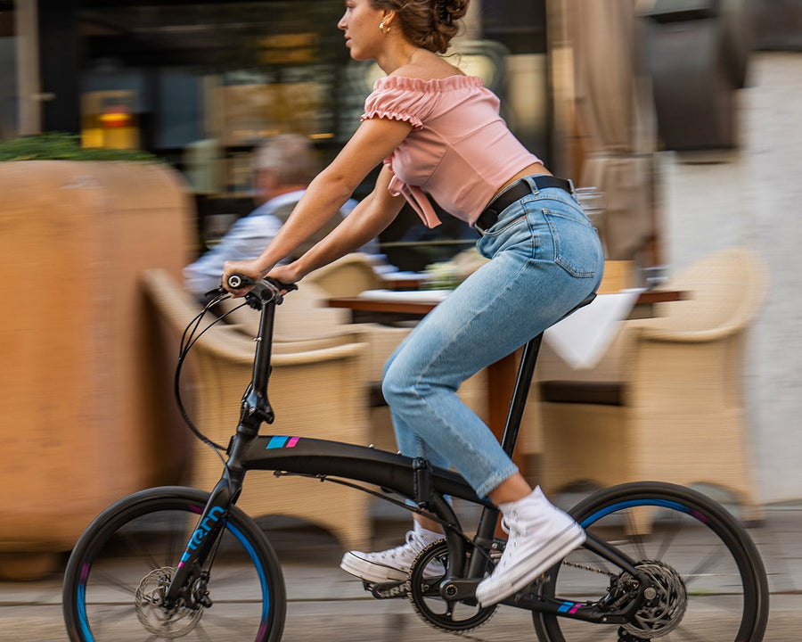 A person riding a Tern Verge folding bike on a blurred background.
