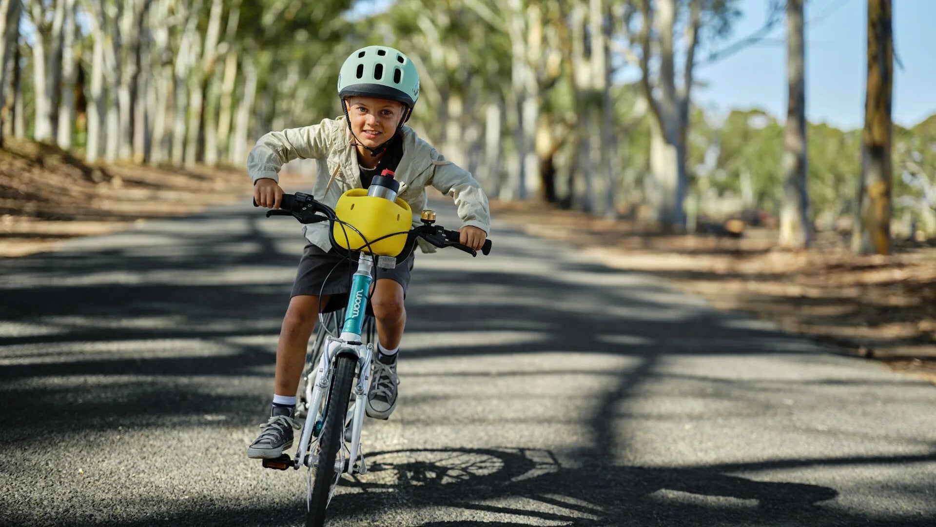 Child riding a bicycle on a path with trees in the background