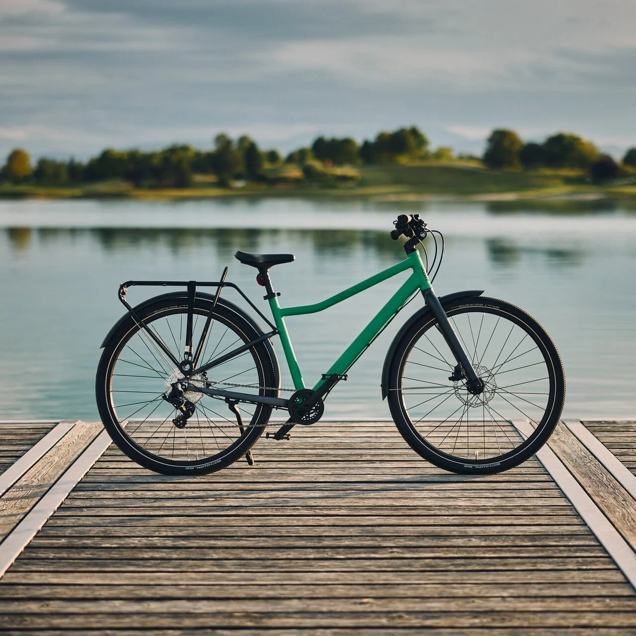 Green bicycle on a wooden dock by a lake with trees in the background