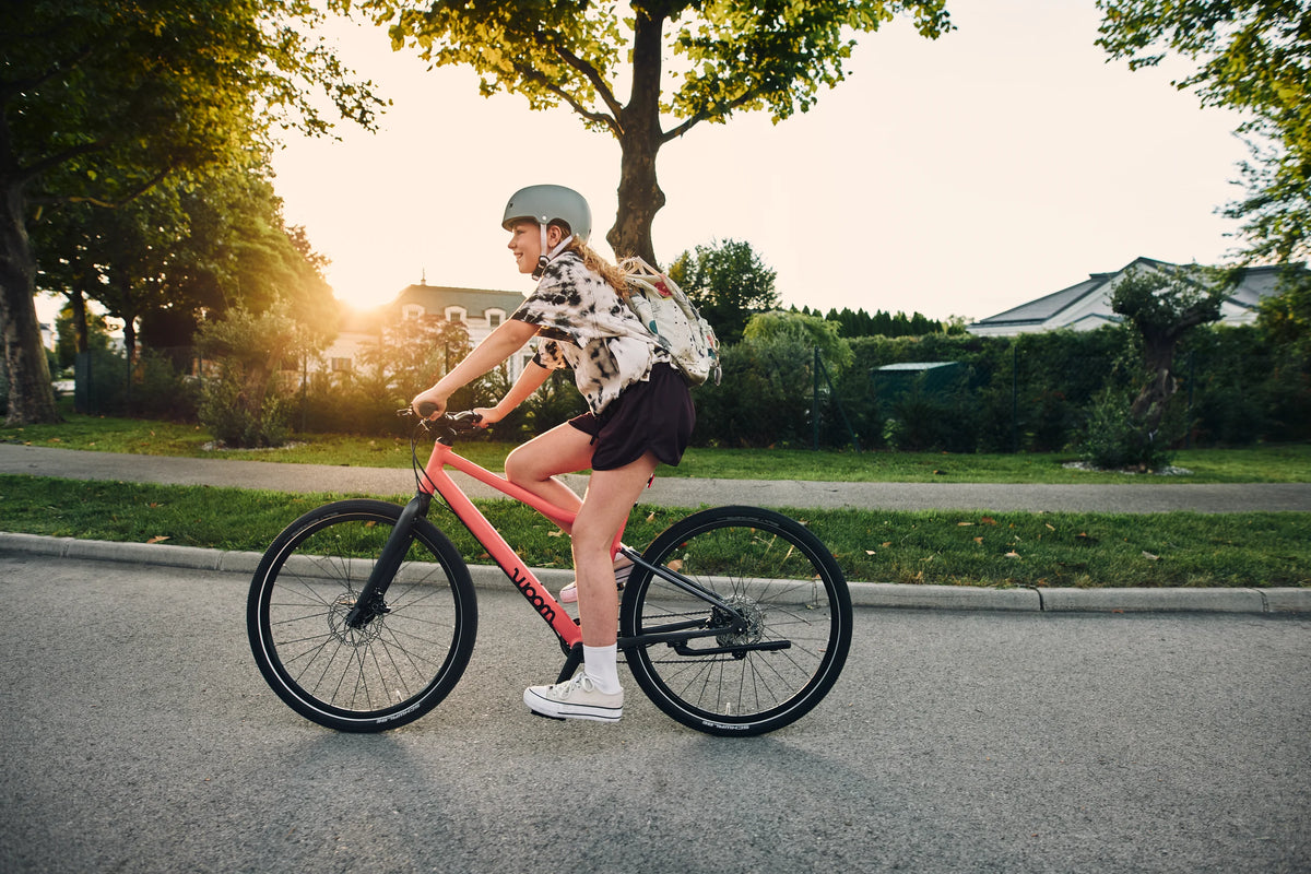 Person riding a bicycle on a suburban street with trees and houses in the background