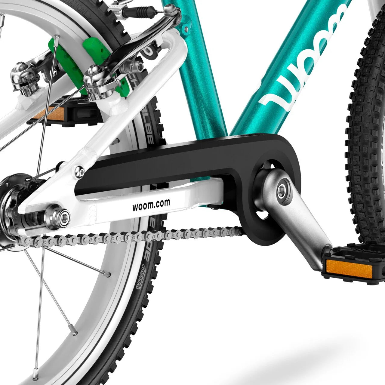Close-up of a Woom bicycle pedal and chain on a white background with 'woom' branding.