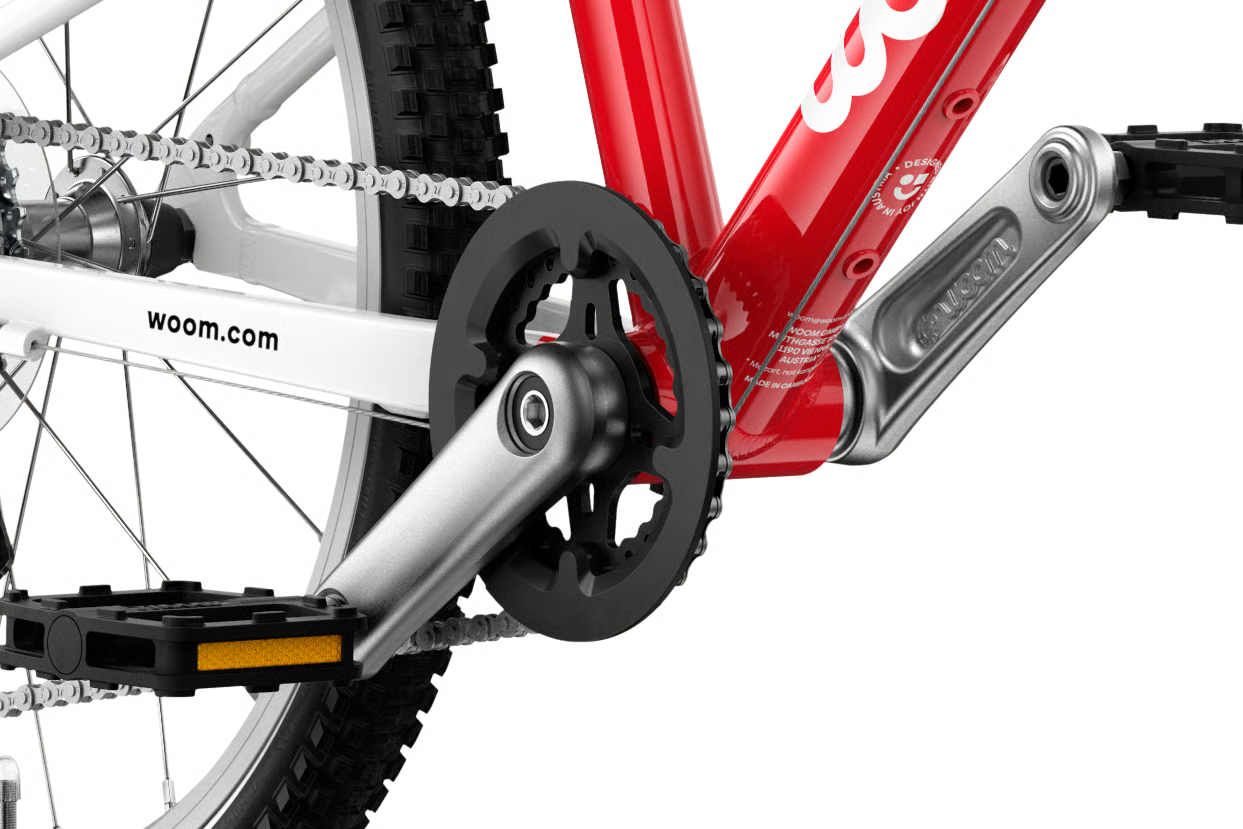 Close-up of a Woom bicycle chain and gear system with 'woom.com' branding.