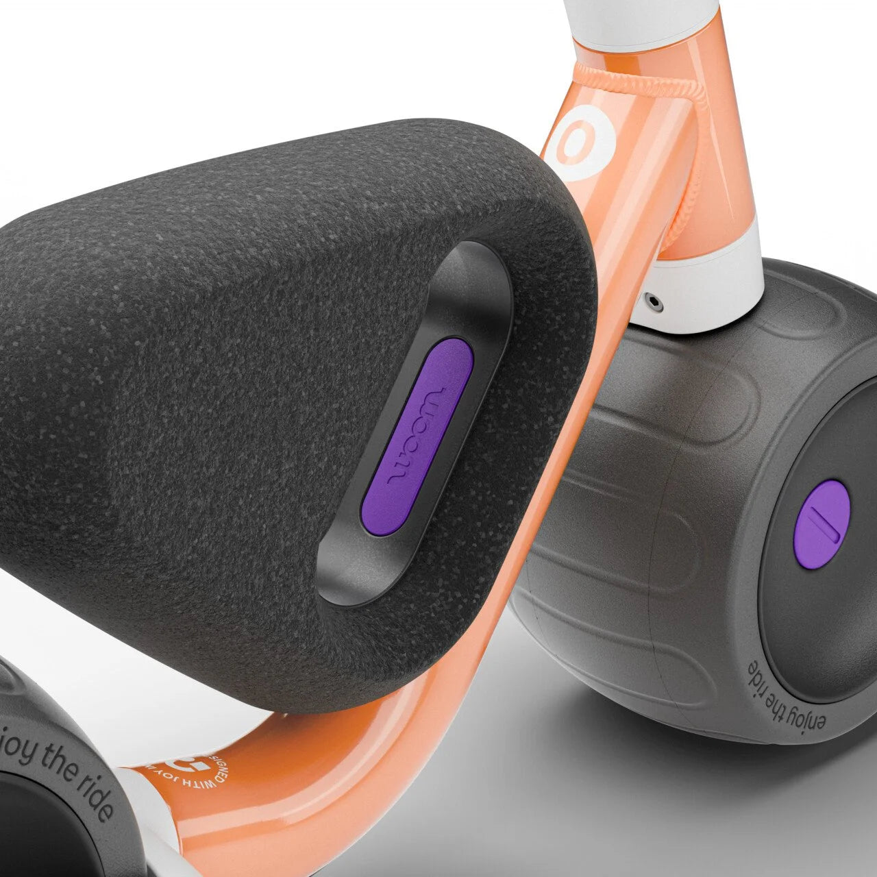 Close-up of a Woom balance bike seat with a purple brand logo on a white background