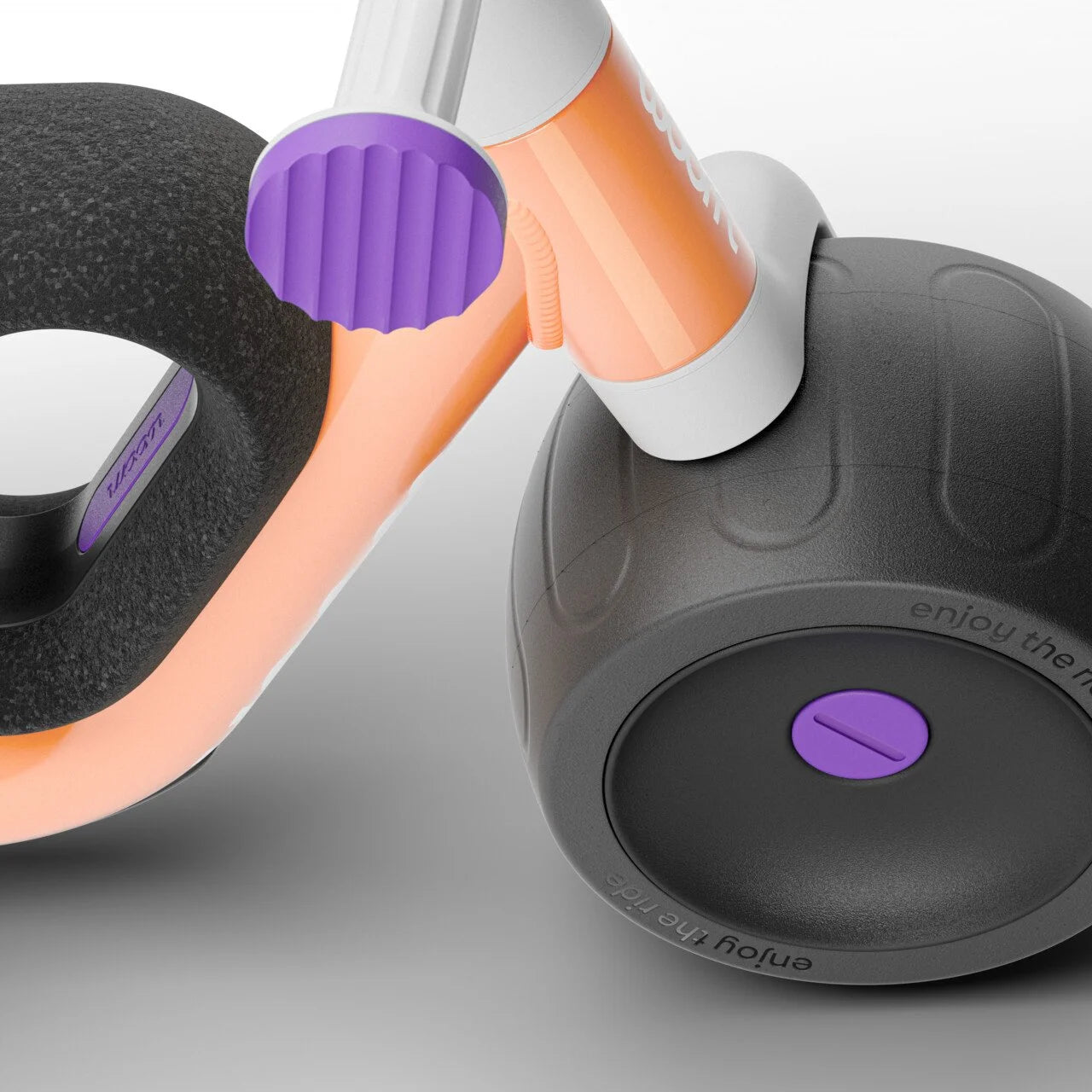 Close-up of a black and orange balance bike wheel with purple accents on a grey background