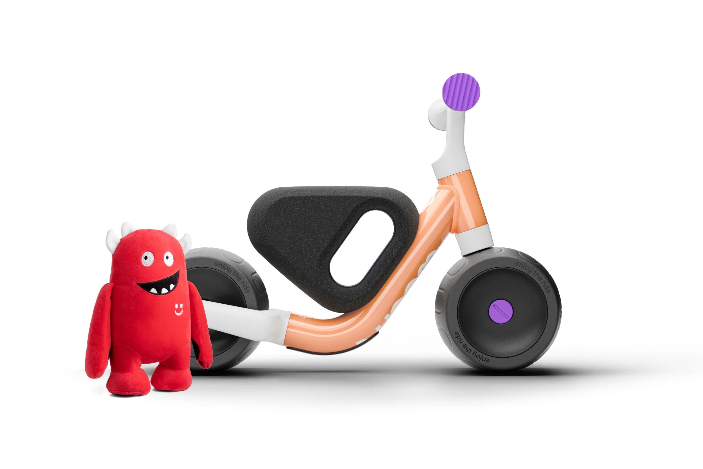 Children's Woom balance bike with a red plush toy on a white background