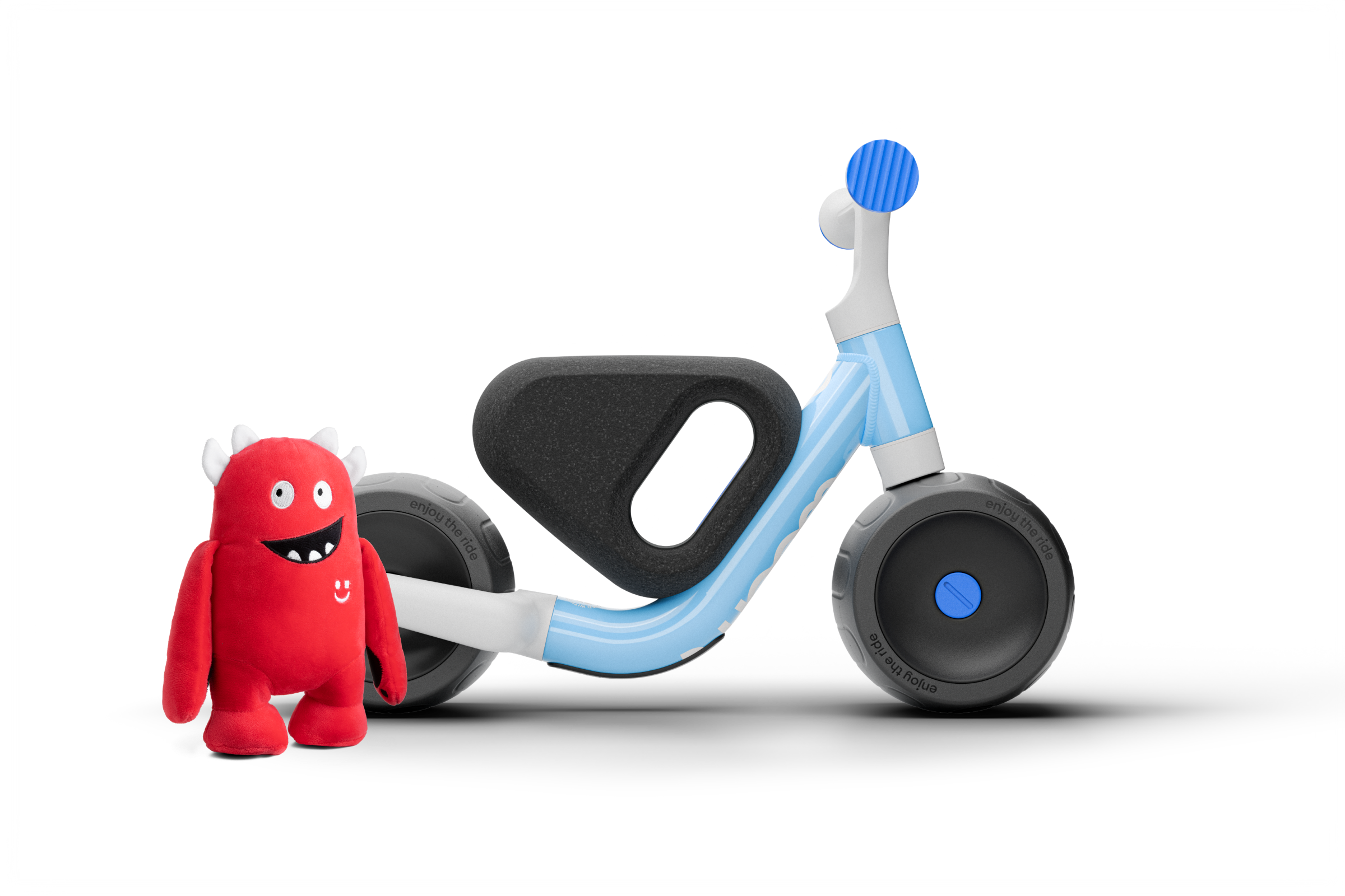 Children's Woom balance bike with a red toy figure on a white background