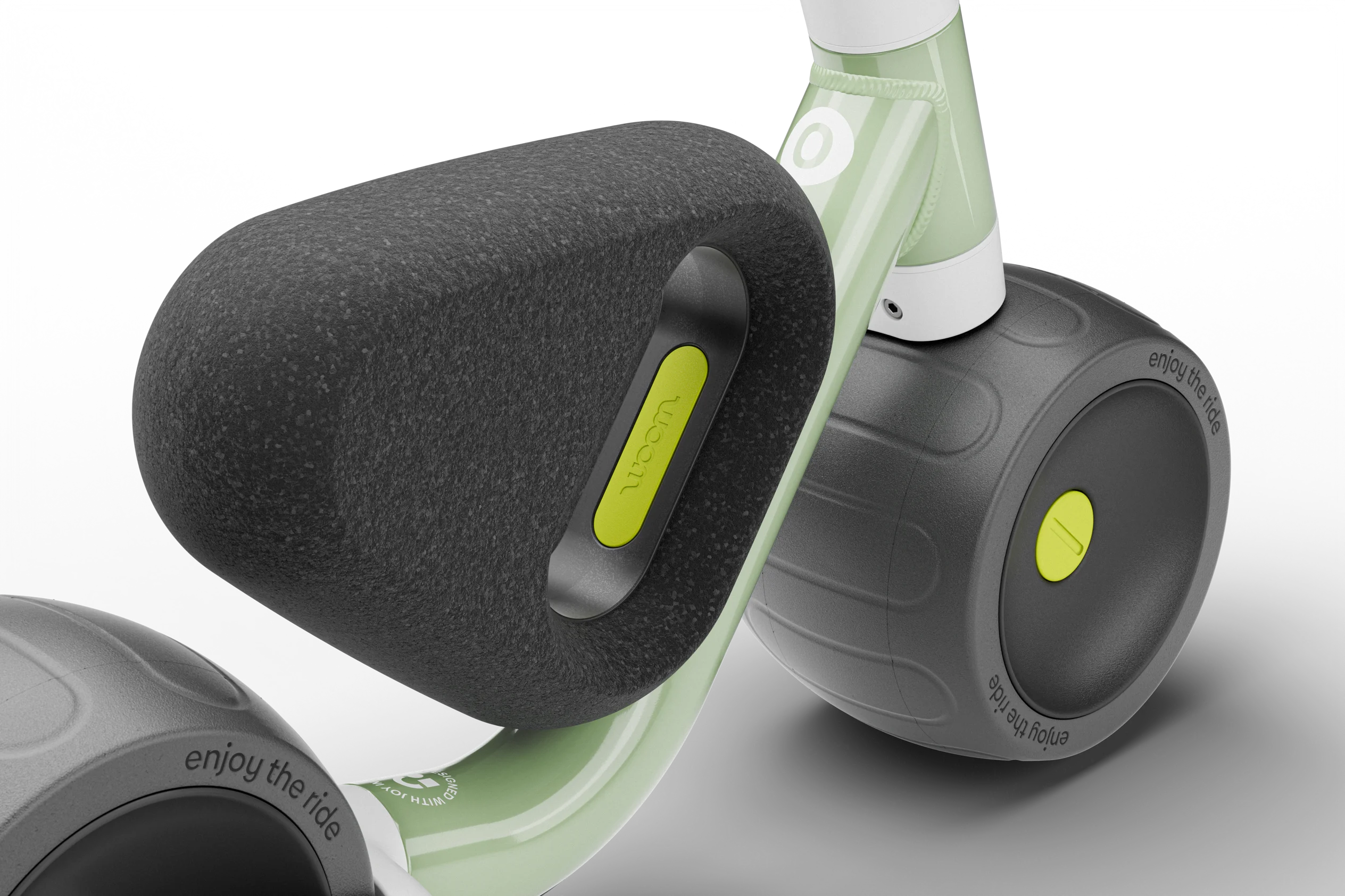 Close-up of a Woom balance bike with black wheels and green accents on a transparent background