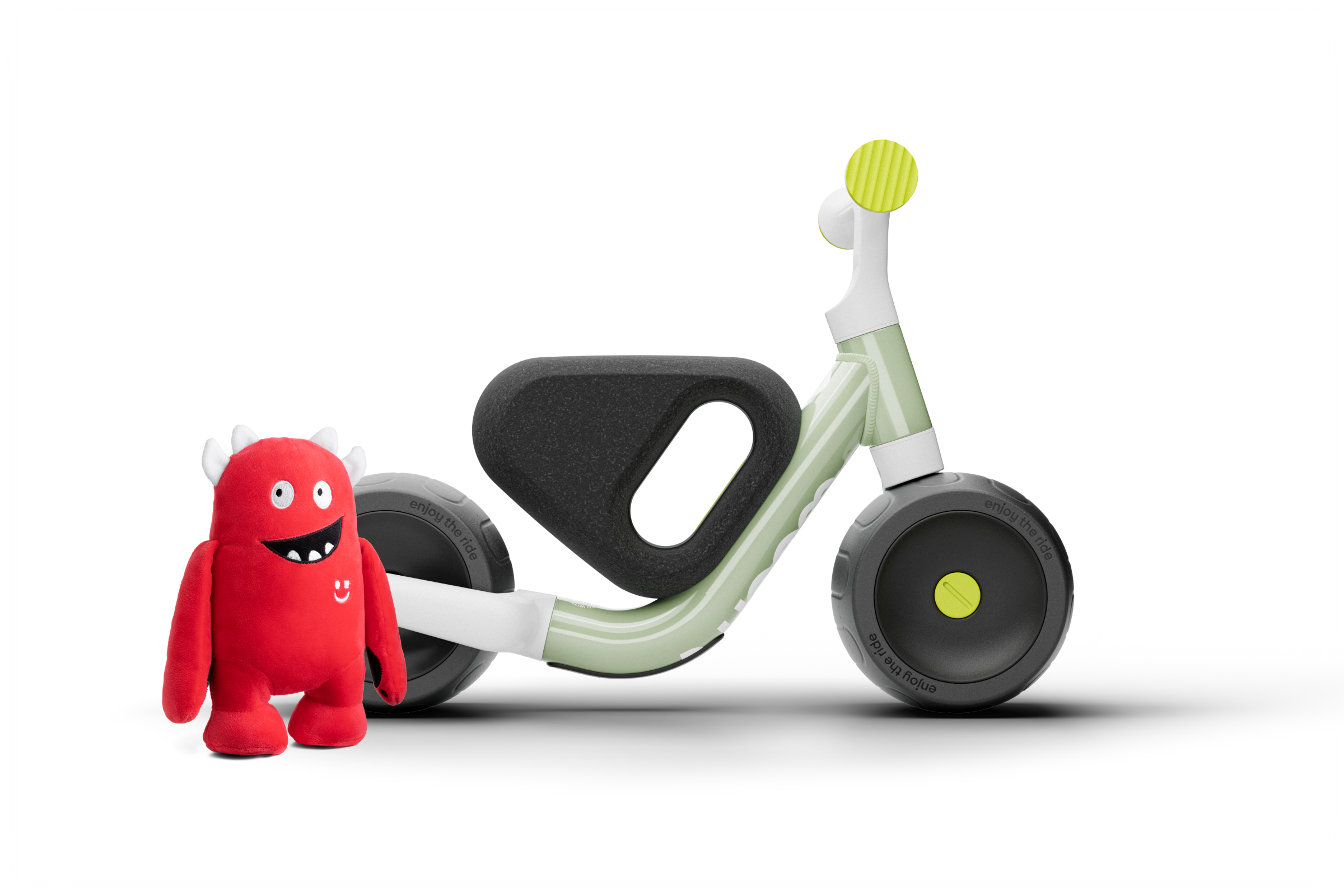 Children's Woom balance bike with a red plush toy on a white background