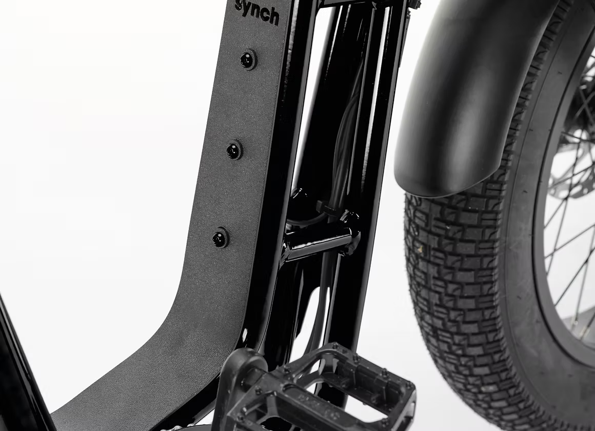 Close-up detail of a black bicycle frame showing the seat post, seat tube, pedal platform, and part of the tire against a white studio background.
