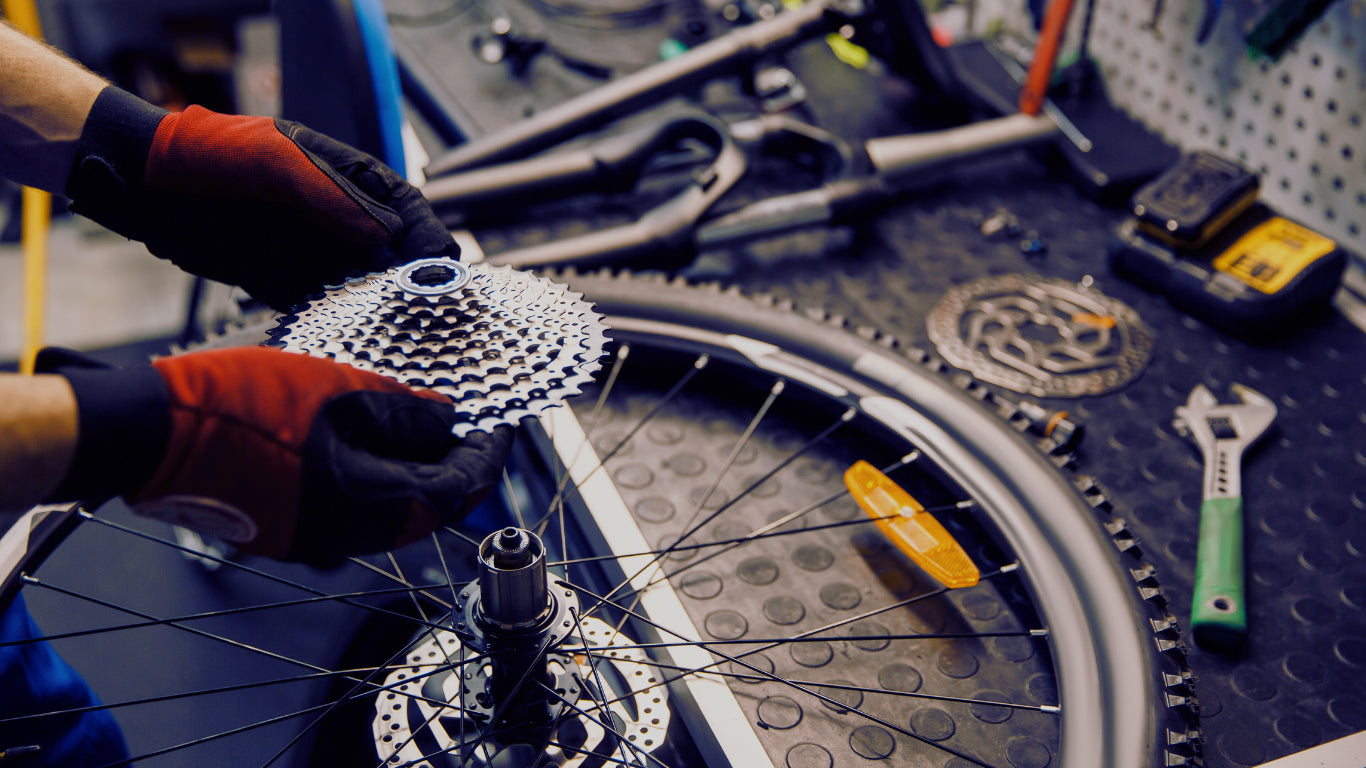 Person working on a bicycle wheel with tools in a workshop setting