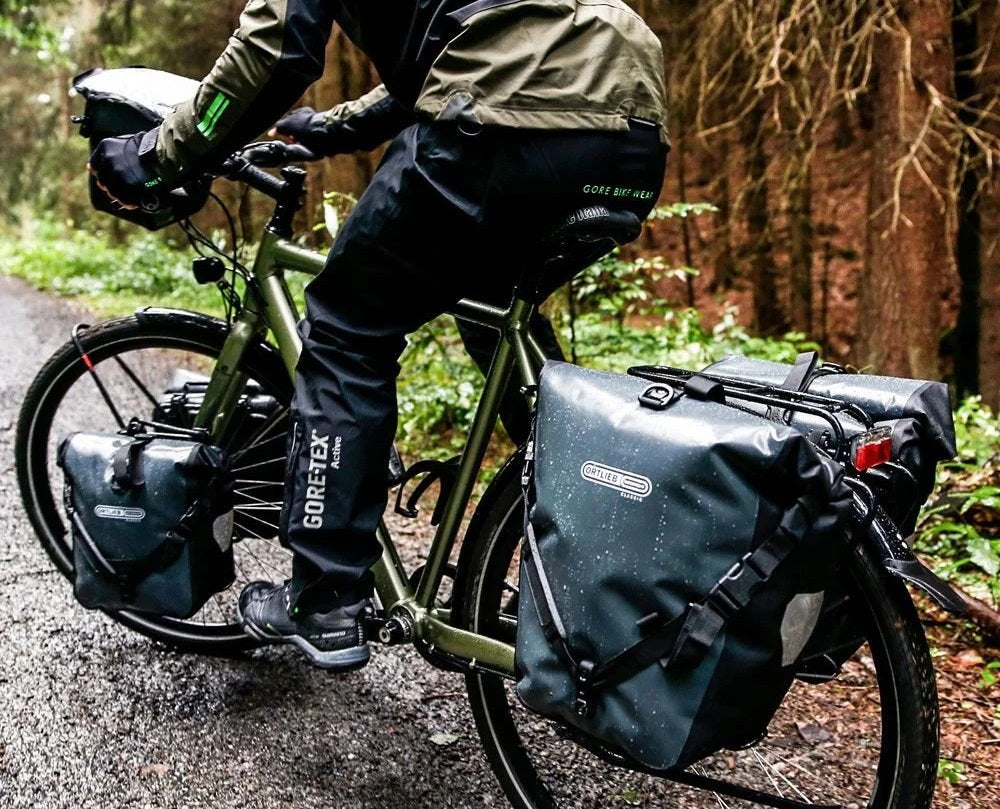 Person riding a bicycle with panniers on a forest path