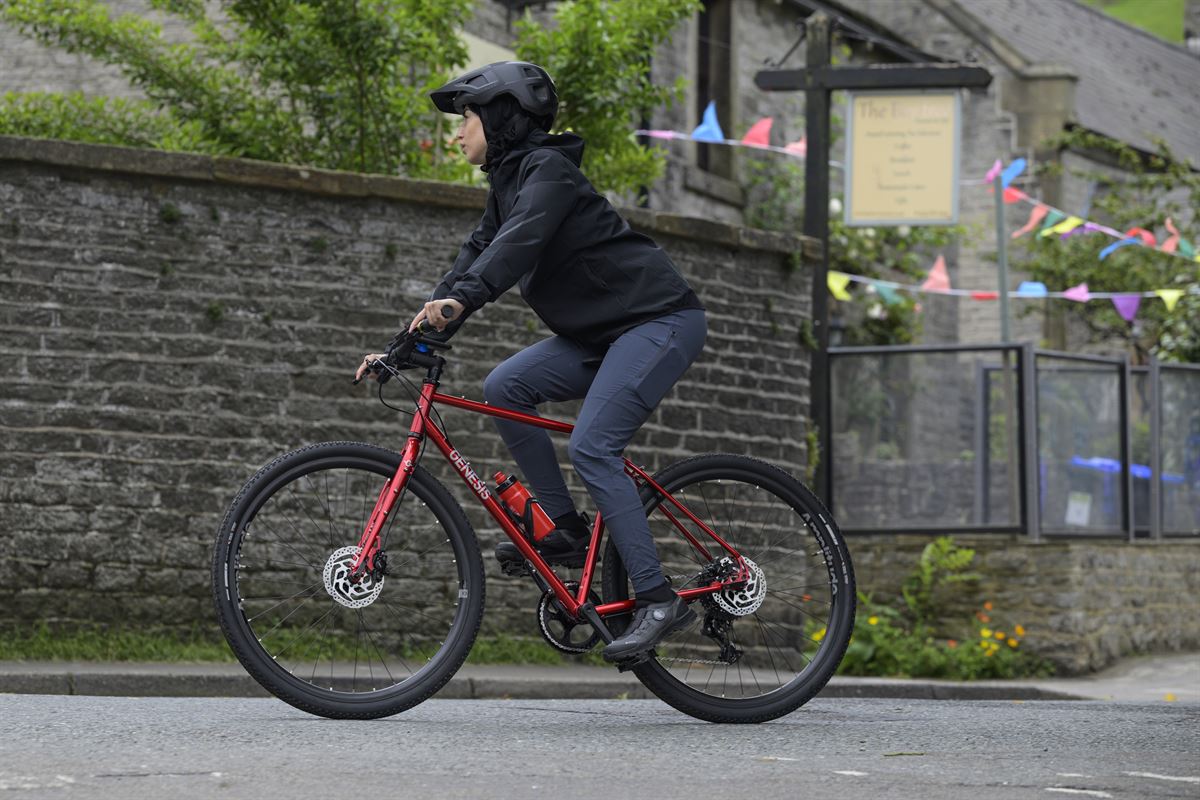 Person riding a red bicycle on a street with a building and flags in the background