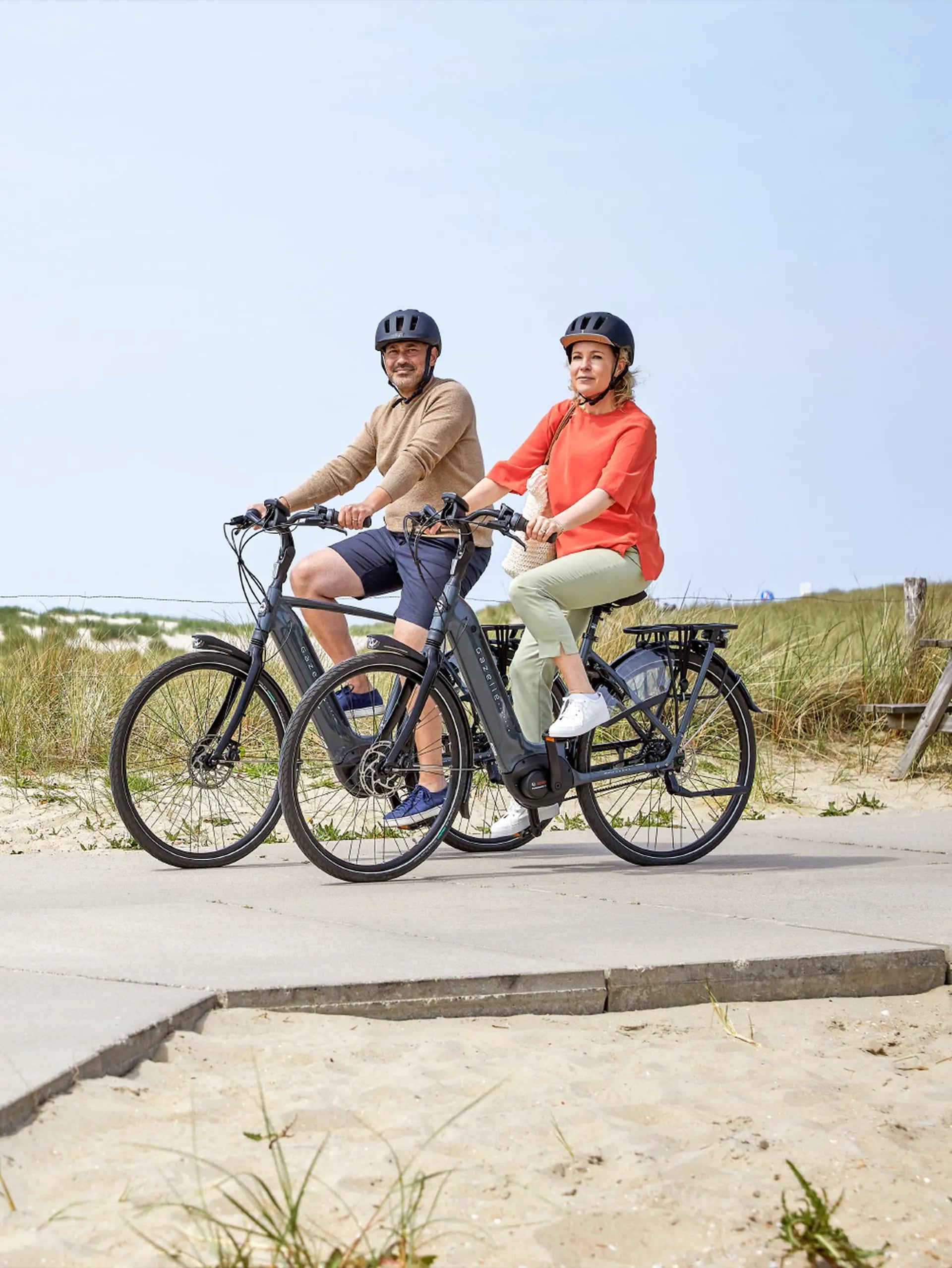 Two people cycling on Gazelle Grenoble bicycles by the sea side.