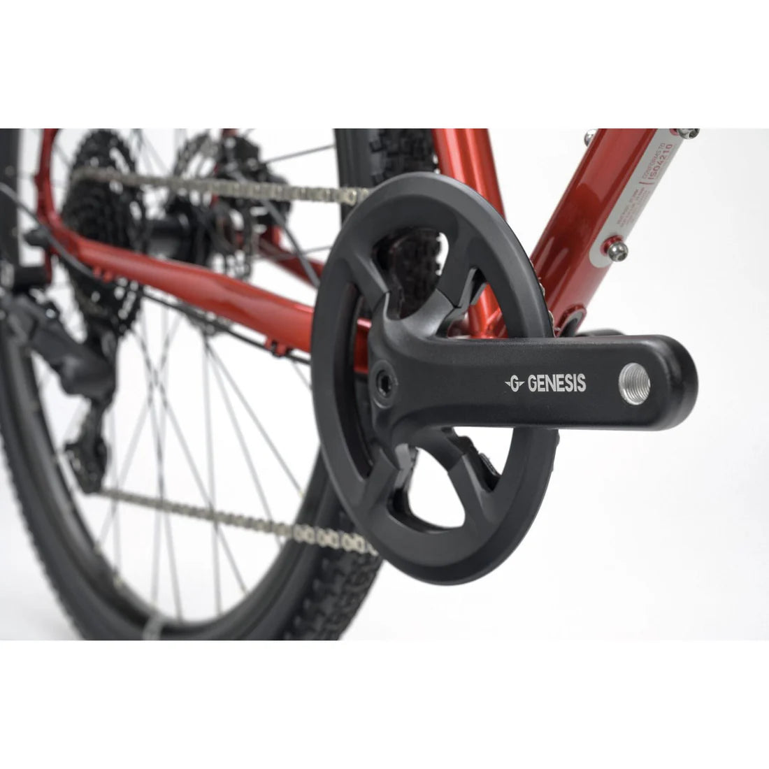 Close-up of a bicycle chain and gear system with 'Genesis' branding on a white background