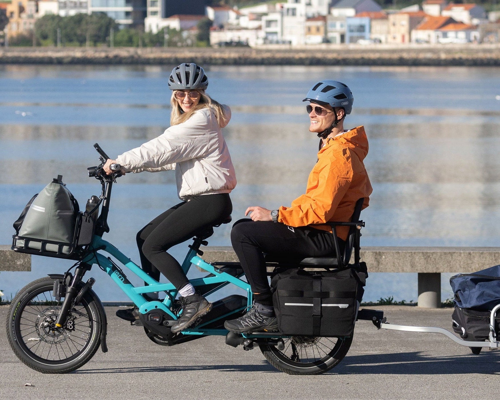 Couple riding a Tern cargo electric bike by the river.