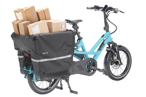 A turquoise and black Tern cargo bike with a rear cargo box loaded with boxes on a white background.
