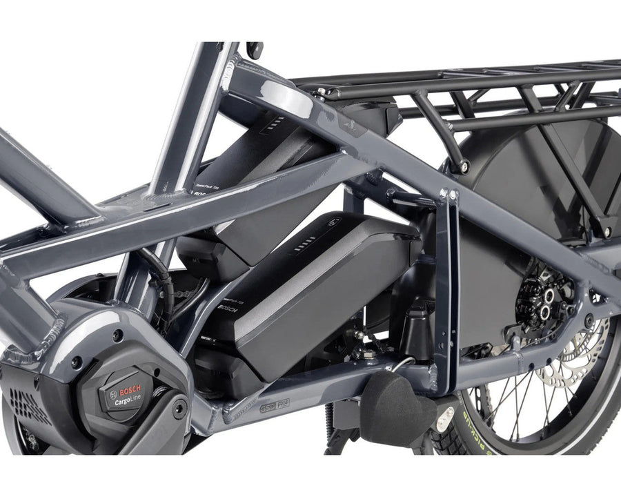 Close-up of a Tern cargo bike frame with a large black battery mounted in the frame, a rear cargo rack, and part of the rear wheel on a white background.