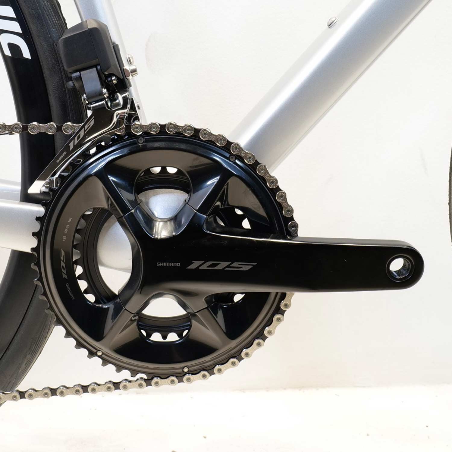 Close up of a bicycle chain ing and crank with a silver bike frame on a white background 