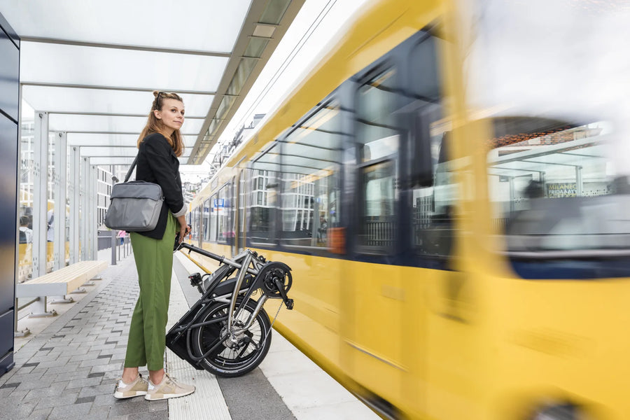 Woman with a folding bicycle and yellow tram