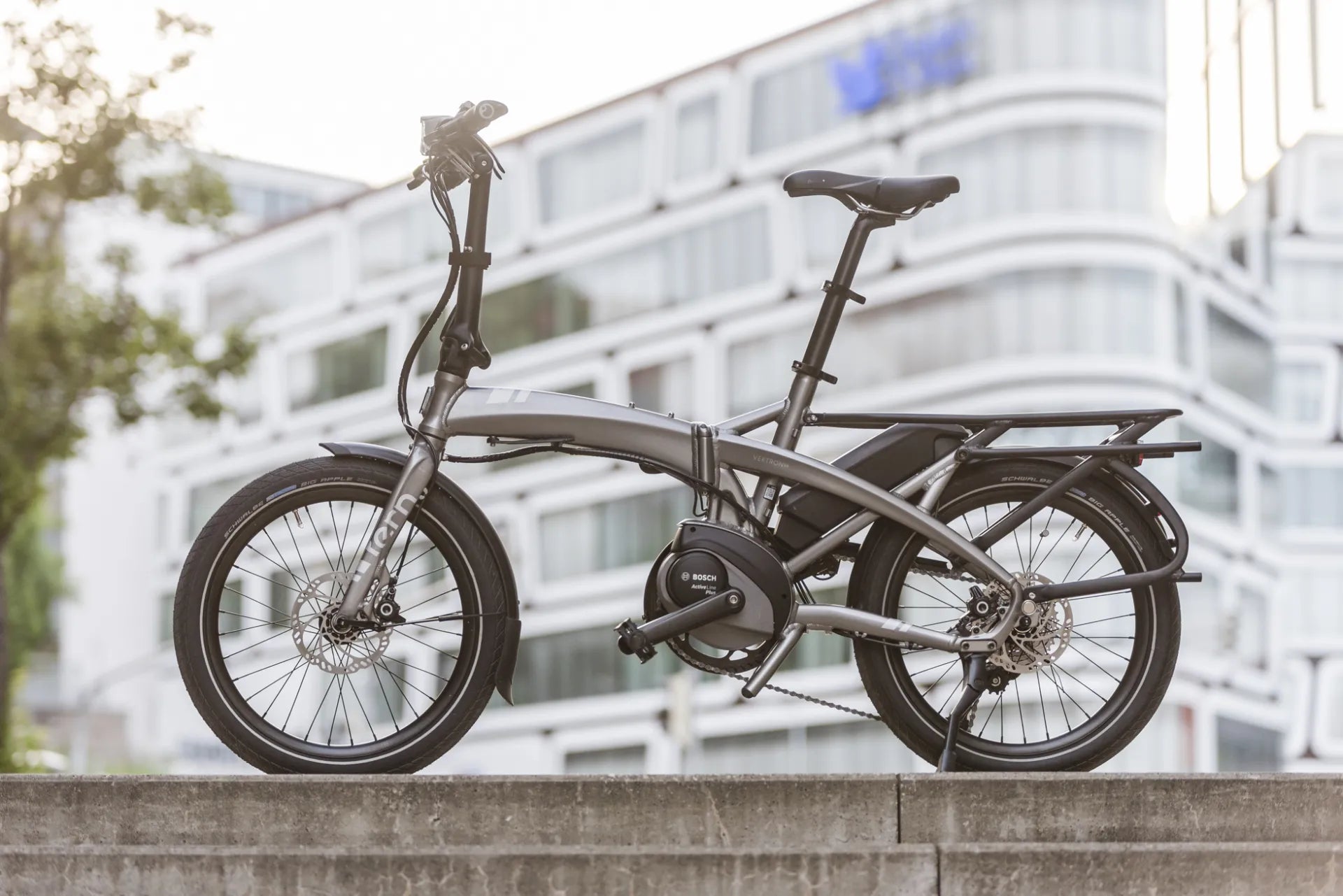 Foldable bicycle on a ledge with a blurred building in the background