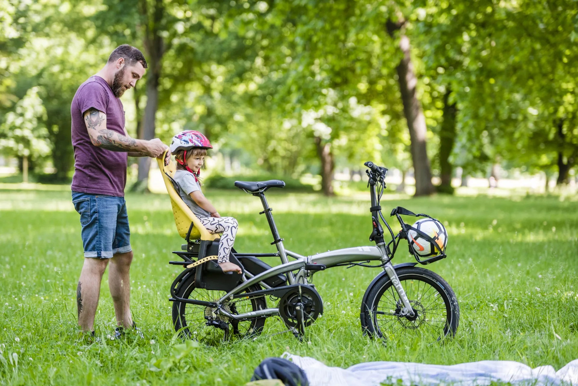 Man with child in a bike seat in a park