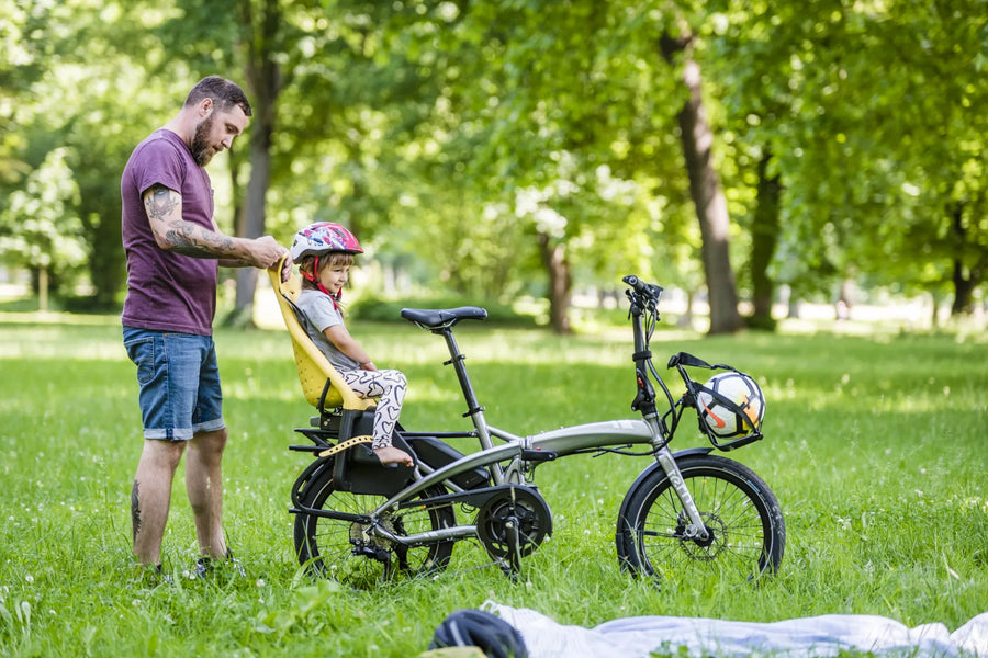 Man with child in a bike seat in a park